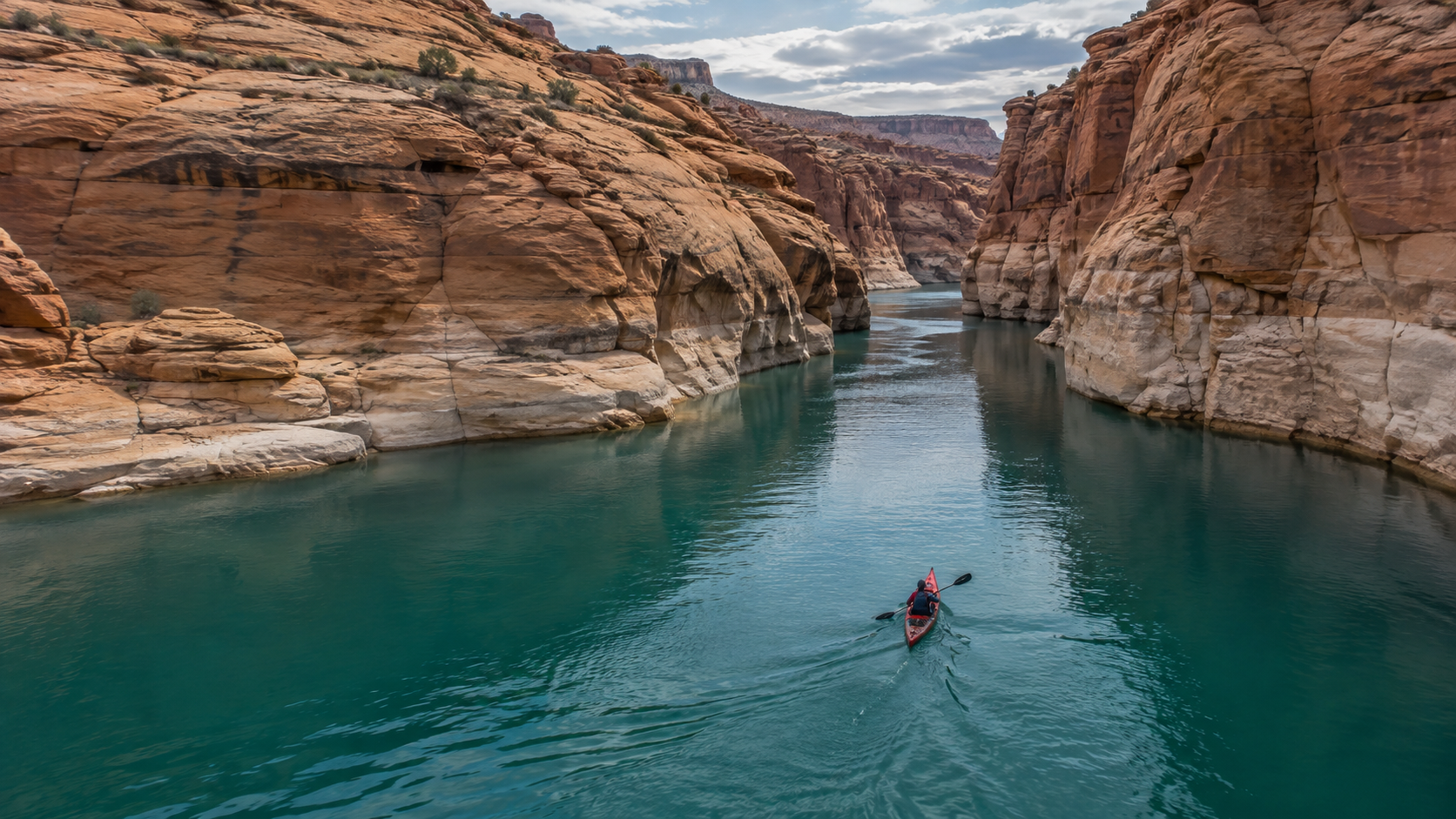 Un kayak rouge approche d’un étroit canyon de grès